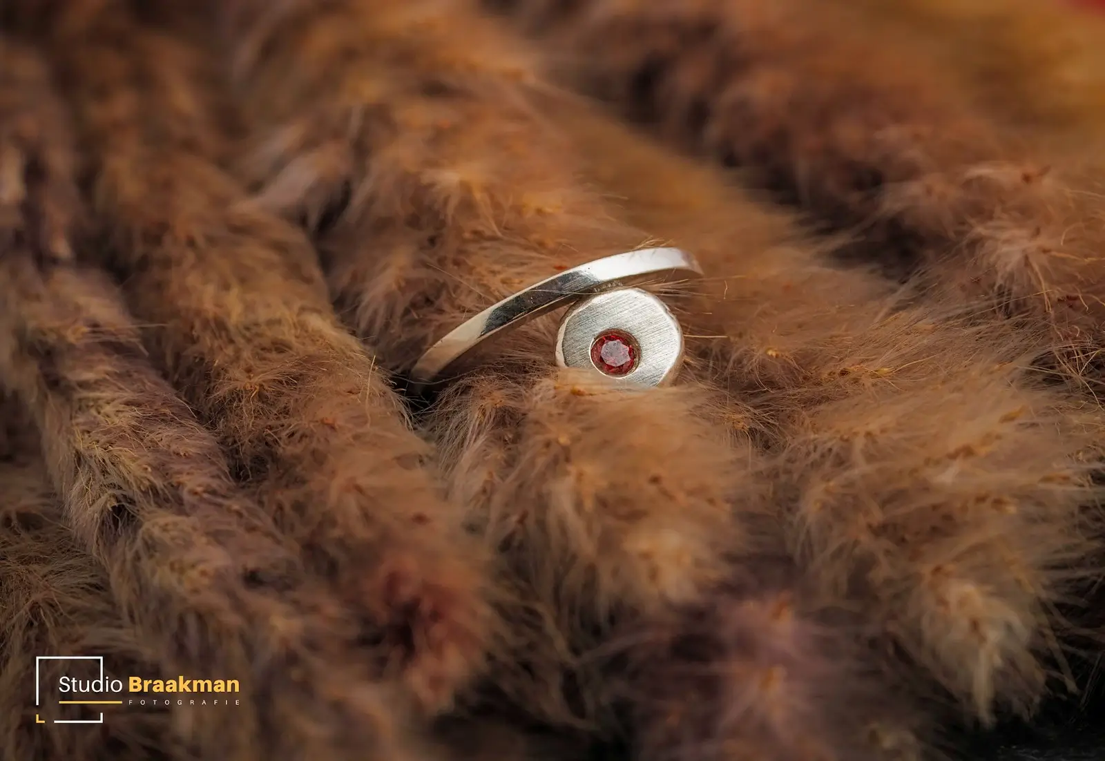 Ring met steen inleg op macroniveau gefotografeerd op een dekentje van pluizenveren