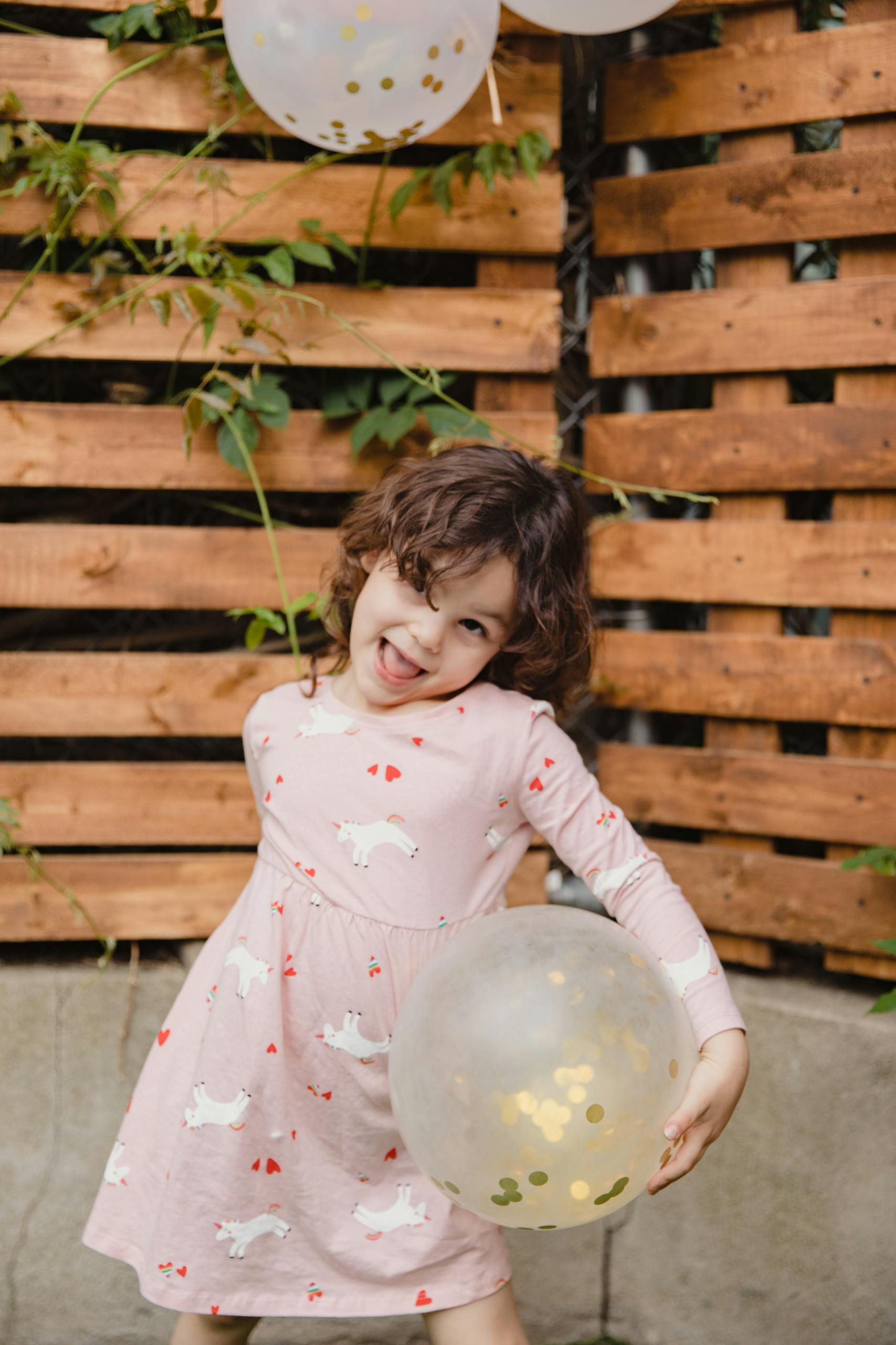 Cheerful child posing with balloons at an outdoor birthday celebration.